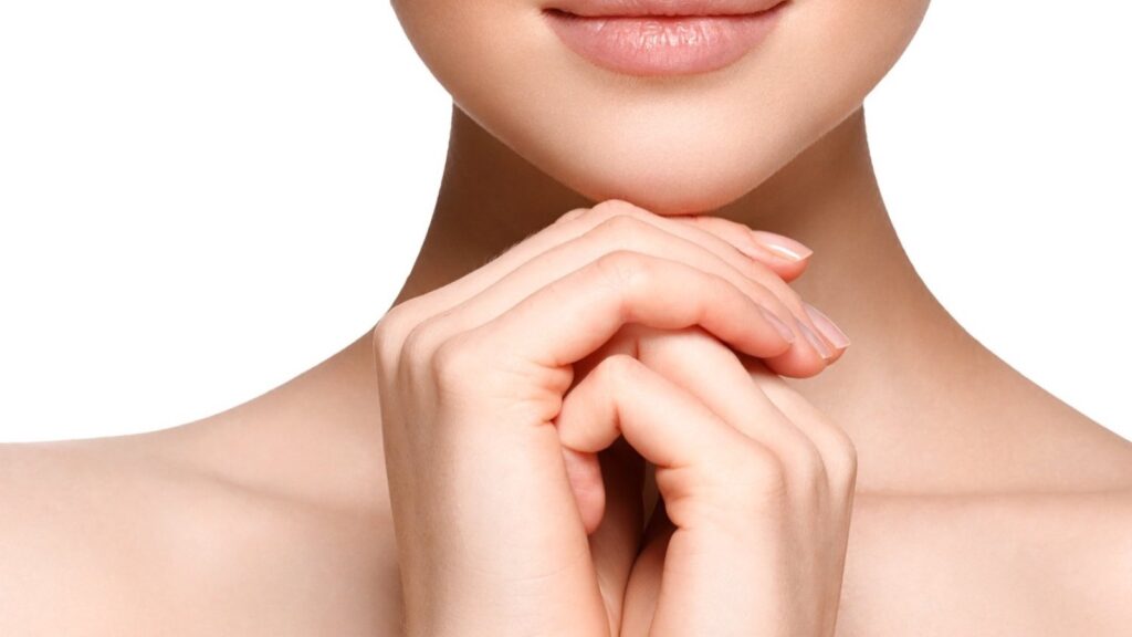 Close-up of a woman's chin and neck, with her hands clasped beneath her chin
