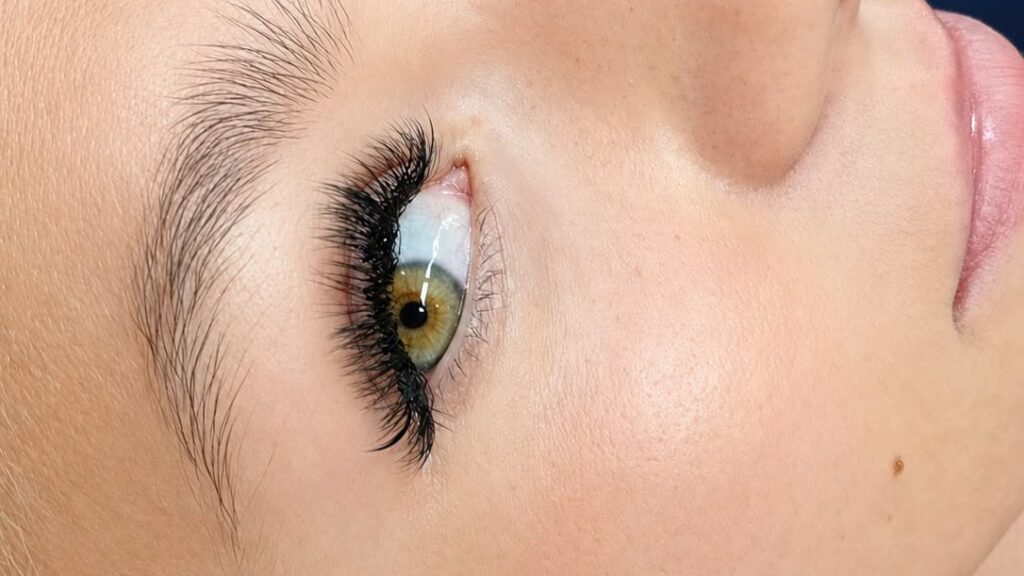 Side view of a woman's eye with full, dark lash extensions