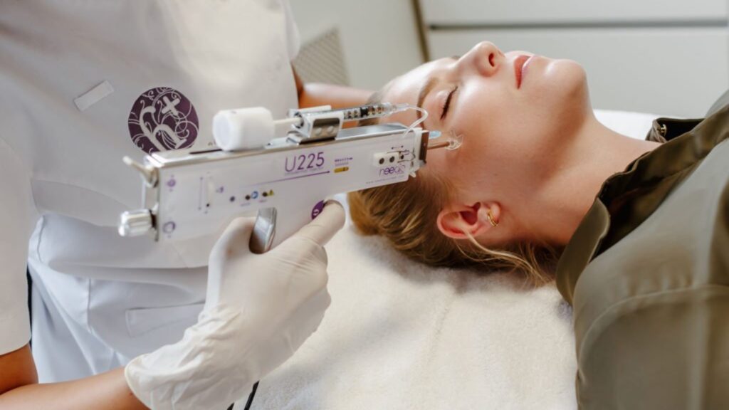 Practitioner using a mesotherapy injector device on a client's face