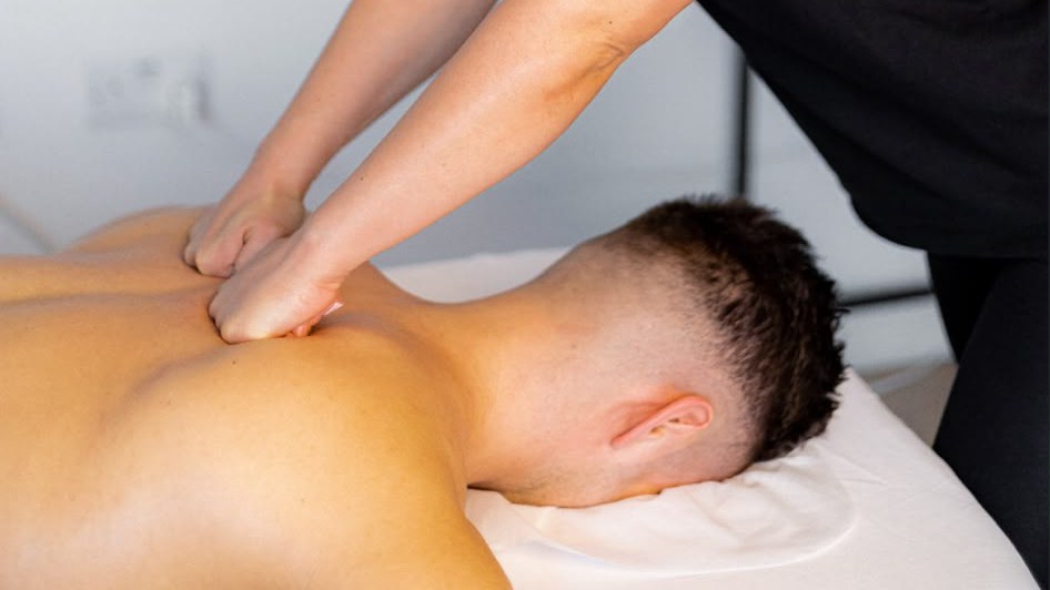 Massage therapist working into a client's upper back with her forearm